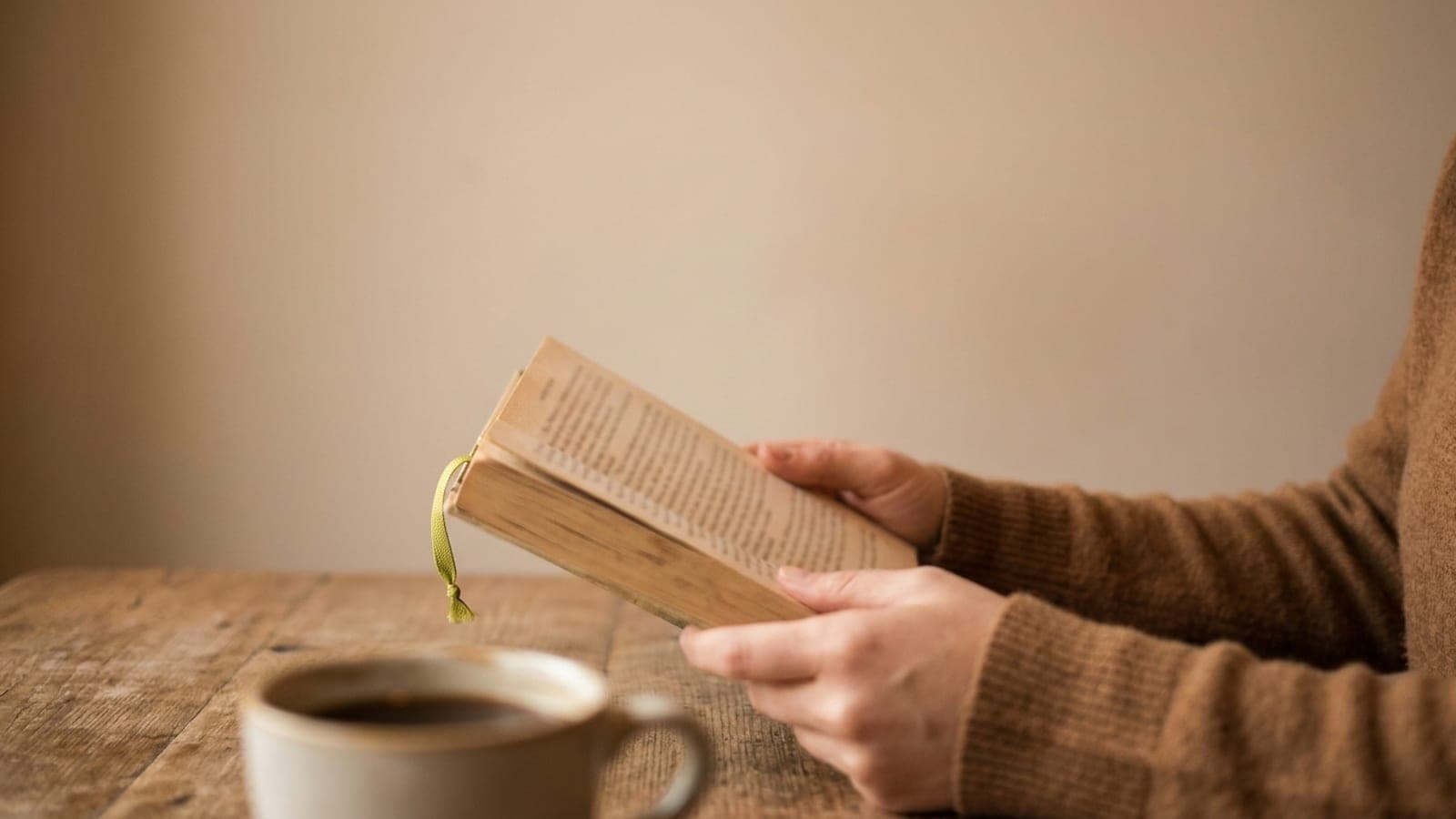 Руки держат открытую книгу за столиком кафе